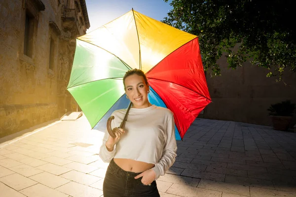 무지개 색깔의 우산을 즐거운 미소를 카메라 공간을 바라보고 아름다운 아가씨의 로열티 프리 스톡 이미지