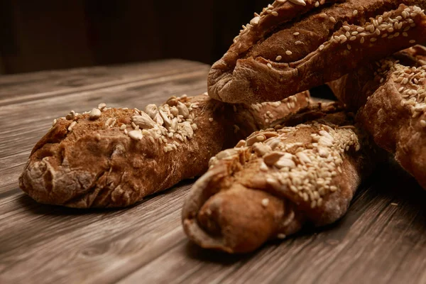 Ahşap arka planda dört somun ekmek, yakın plan. Somunlar, yemek, tohumlar, susam, ev yapımı, ekmek, ekmek