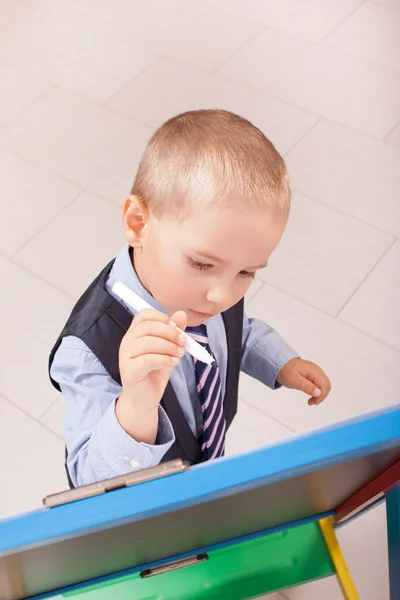 Traje de niño pequeño trabajando en la pizarra —  Fotos de Stock