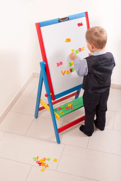 Anzug für kleinen Jungen, der an der Tafel arbeitet — Stockfoto