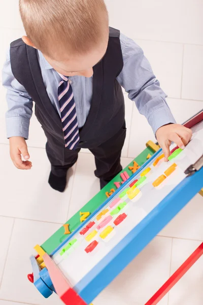 Dobierz odpowiednie wyposażenie na małe młody chłopak pracuje na tablicy — Zdjęcie stockowe
