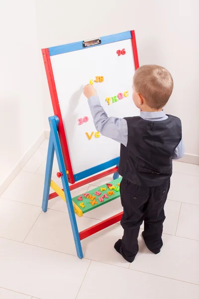 Suit up small young boy working on the chalkboard Stock Picture