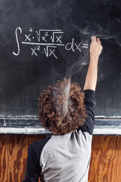 Tänkande pojke lösa ekvationen med rökning huvud och blackboard — Stockfoto