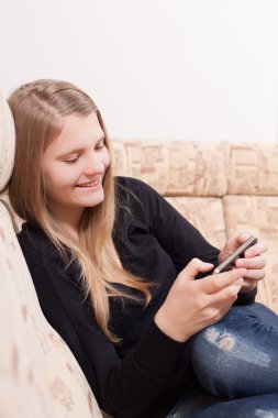 oturma odasında kanepede otururken cep telefonu ile mutlu teen