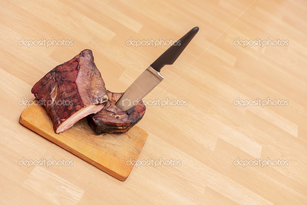 Homemade smoked meat on wooden cutting board with big knife Stock Photo by  ©TomasMikula 18118017