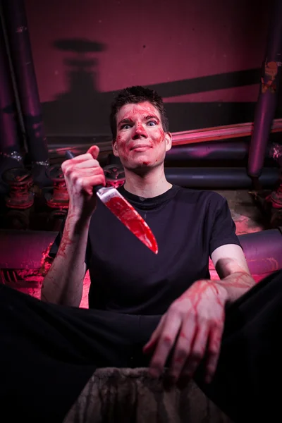 Tueur d'horreur avec couteau dans une pièce sombre avec tuyaux et lumière rouge — Photo