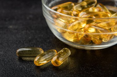 Siyah zemin üzerinde Omega-3 kapsülleri yığını.