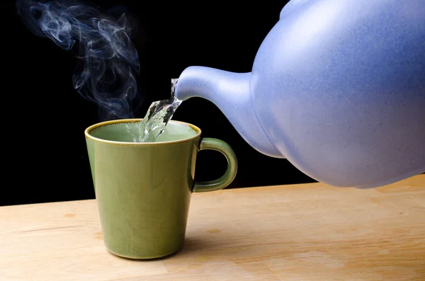Pouring steaming hot tea in a cup — Stock Photo, Image