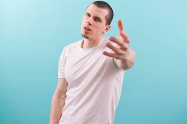 Bir ay boyunca kameraya elini uzatan beyaz, genç bir adam. Poz veriyorum. Modellik. - Temiz. Deri. Tutuyorum. Başarmak için. Geniş aç. Bekar. Esniyorum. Deniyorum. Çekici. Hippi. Kol. Harika.