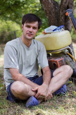 onun orchard bir püskürtücü ile çiftçi