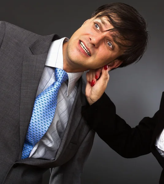 Una mano tirando de una oreja de hombre de negocios — Foto de Stock