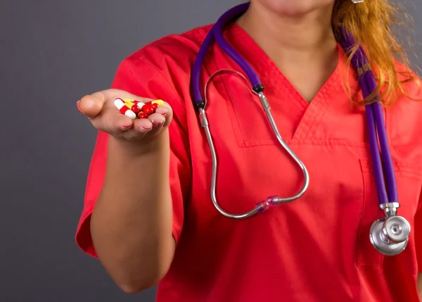 Femmina medico o infermiere con stetoscopio in possesso di pillole nel suo ha — Foto Stock