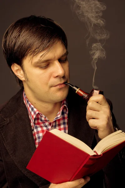 Портрет мужчины, читающего и курящего трубку — стоковое фото