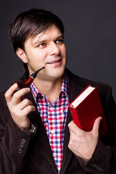 Portrait of a man holding a book while smoking a pipe — Stock Photo, Image