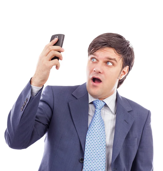 Joven hombre de negocios sosteniendo un teléfono móvil y mirando sorprendido — Foto de Stock