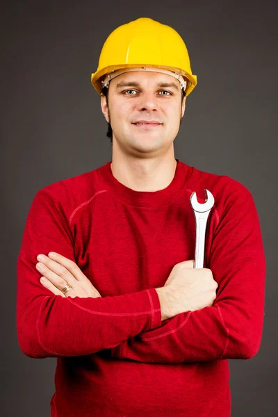 Lächelnder junger Mechaniker mit seinem Schraubenschlüssel — Stockfoto