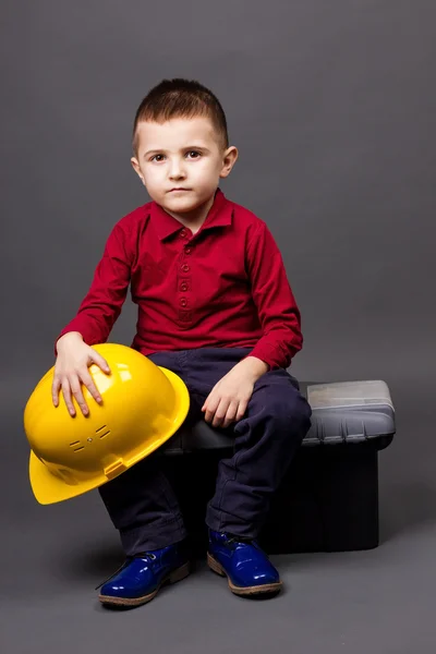 Niño serio con casco sentado en una caja de herramientas —  Fotos de Stock