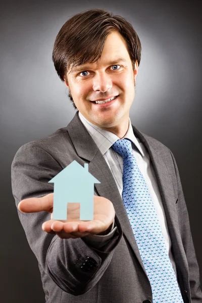 Jeune homme d'affaires tenant un modèle de maison sur sa paume — Photo