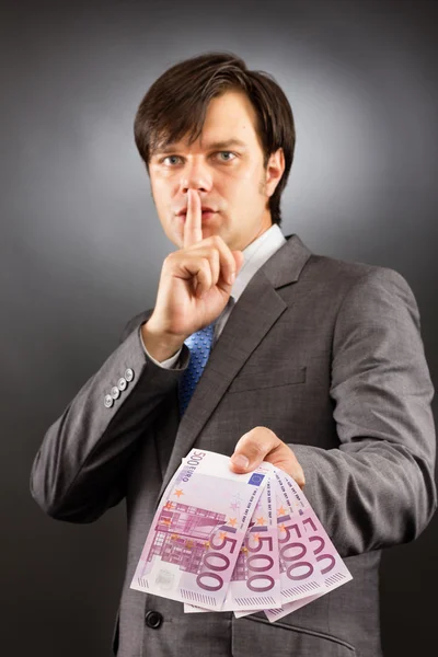 Young businessman making silence gesture and holding euro bankn — Stock Photo, Image