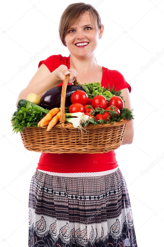 Happy young woman holding basket with fresh vegetables