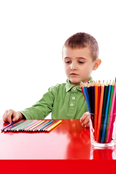 Netter kleiner Junge mit vielen Buntstiften am Tisch — Stockfoto