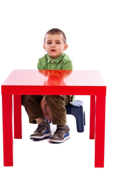 Adorable niño en la mesa mirando a la cámara — Foto de Stock