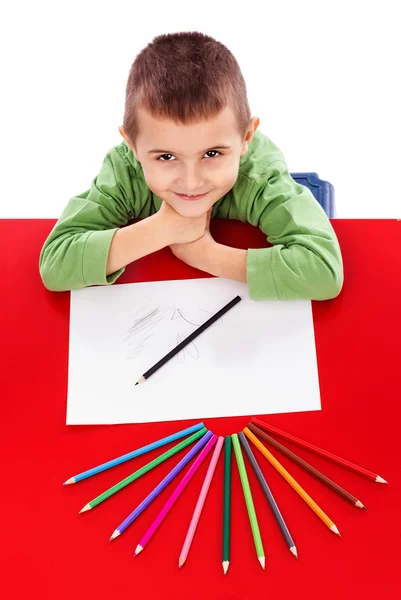 Glücklicher kleiner Junge am Tisch zeichnet mit Buntstiften und sieht u — Stockfoto