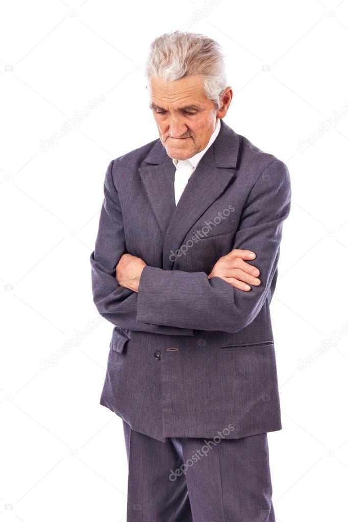 Elderly man with arms folded looking down lost in deep thought