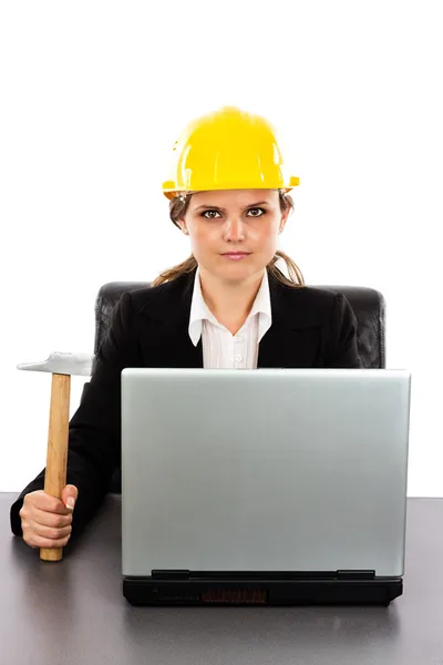 Serious engineer woman with a hammer sitting at desk — Stock Photo, Image