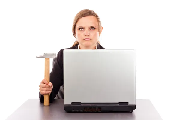 Serious businesswoman with a hammer sitting at office desk — Stock Photo, Image