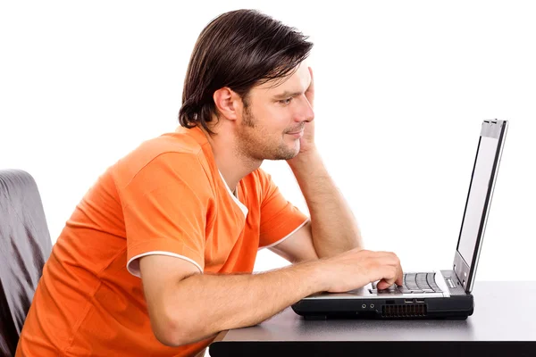 Gelukkig lachend jonge man aan het werk en typen op laptop — Stockfoto