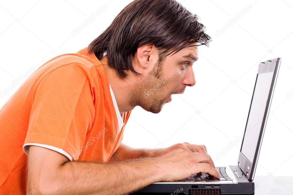 Astonished young man staring at his laptop