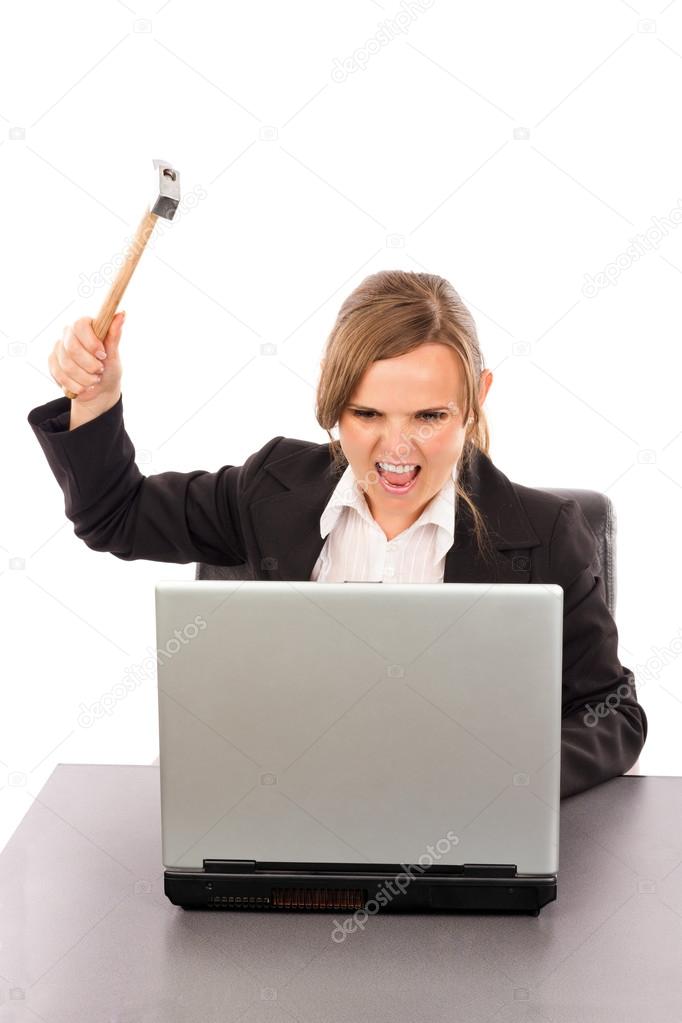 Angry businesswoman with a hammer ready to smash her laptop whil