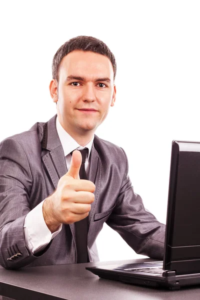 Young businessman sitting at office desk showing his thumb up — Stock Photo, Image