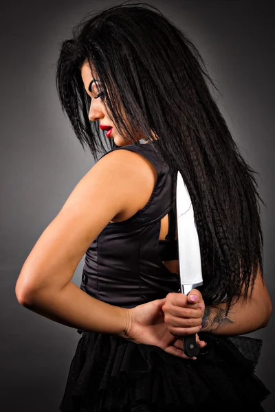 Retrato de una joven expresiva sosteniendo un cuchillo grande a su — Foto de Stock