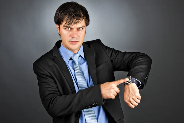 Young businessman pointing to his watch with an angry expression — Stock Photo, Image