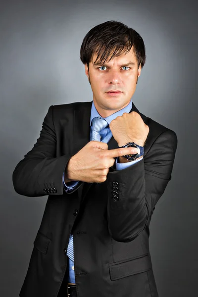 Giovane uomo d'affari indicando il suo orologio con un'espressione arrabbiata — Foto Stock