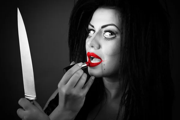 Brunette young woman applying lipstick using the knife as a mir — Stock Photo, Image