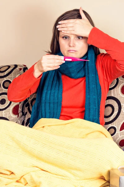 Young woman having flu and checking a thermometer — Stock Photo, Image