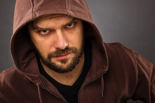 Close-up portrait of threatening man with beard wearing a hood — Stock Photo, Image