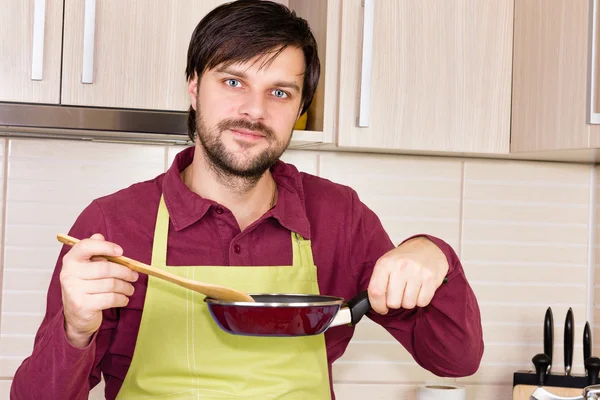 Handsome young with apron cooking in the kitchen — Stock Photo, Image