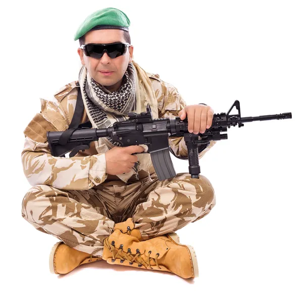 Joven soldado con un arma sentado con las piernas cruzadas — Foto de Stock