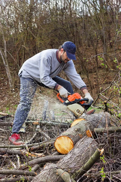 Young man cutting trees using an electrical chainsaw — Stock Photo, Image