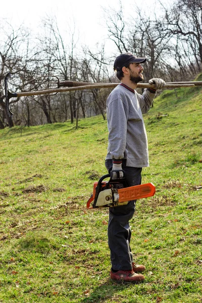 Young man holding an electrical chainsaw, preparing to work — Stock Photo, Image