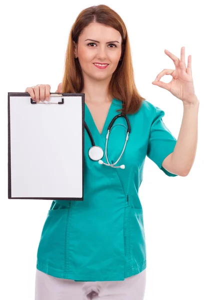 Retrato de uma jovem médica segurando uma área de transferência e mostrando — Fotografia de Stock