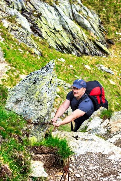 Young man hiking on difficult mountain trail with hanging cable — Stock Photo, Image