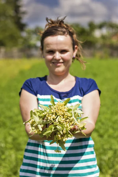 Jeune femme tenant feuille de tilleul et fleur — Photo