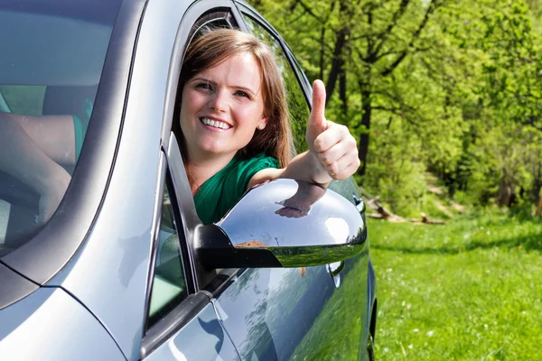 Mooie jonge vrouw met Duimschroef opwaarts in haar nieuwe auto — Stockfoto