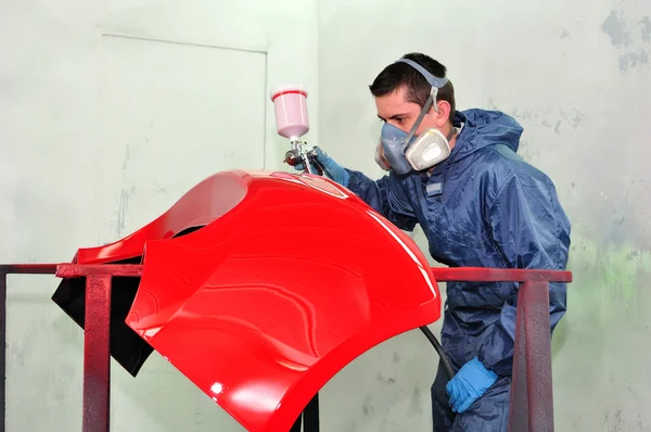 Trabajador pintando un parachoques de coche rojo . — Foto de Stock