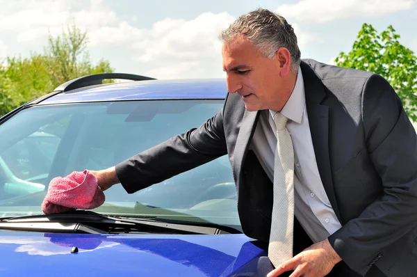 Człowiek ubrany garnitur czyszczenia samochodu. — Zdjęcie stockowe